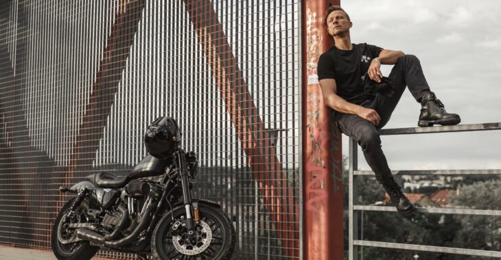 Biker wearing motorcyclist jeans and posing with his bike