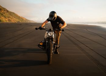man learning how to ride a motorcycle on a beach