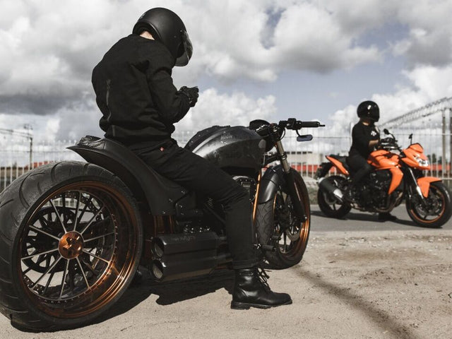 Motorcyclist in protective riding jeans, shown from behind astride a bike—emphasizes fit and real-world use context.