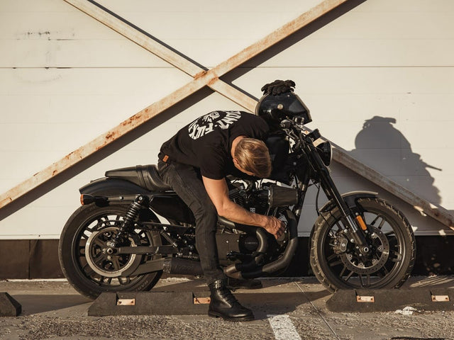 Motorcyclist crouching beside bike wearing riding gear—sets context for CE safety standards guide.