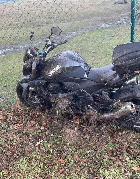 Fallen motorcycle on muddy roadside—the real-world crash setting illustrating risk from slippery patch.