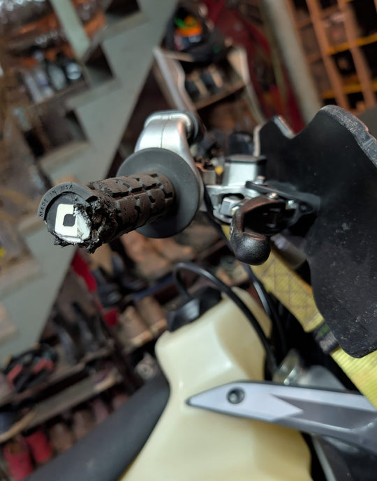Motorcycle handlebar with scuffed grip and scratched handguard after crash