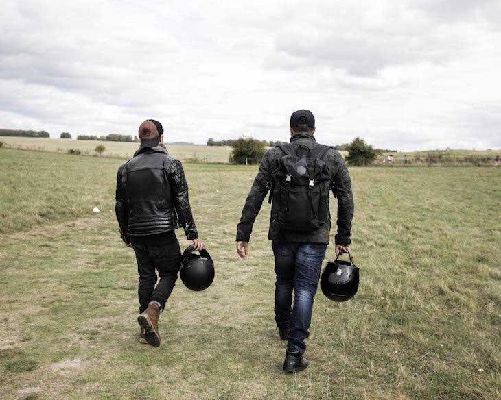 Two bikers walking and carrying their herlmets