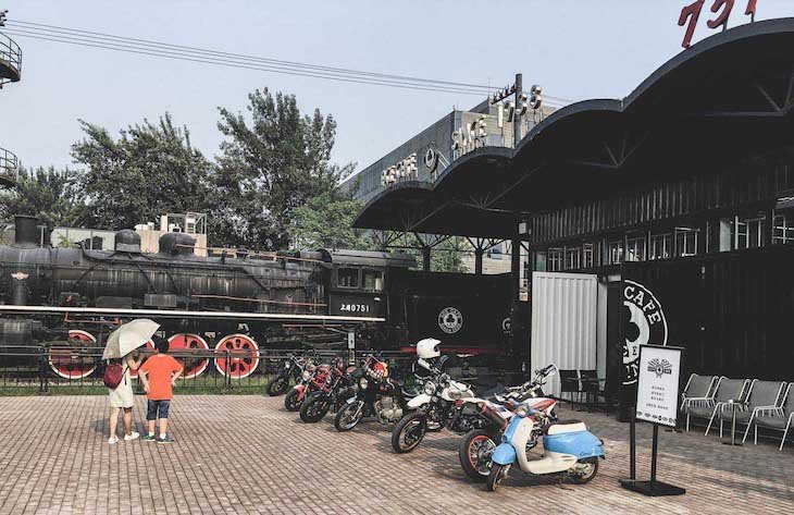 Some old school motorcycles in front of the classical train exposed