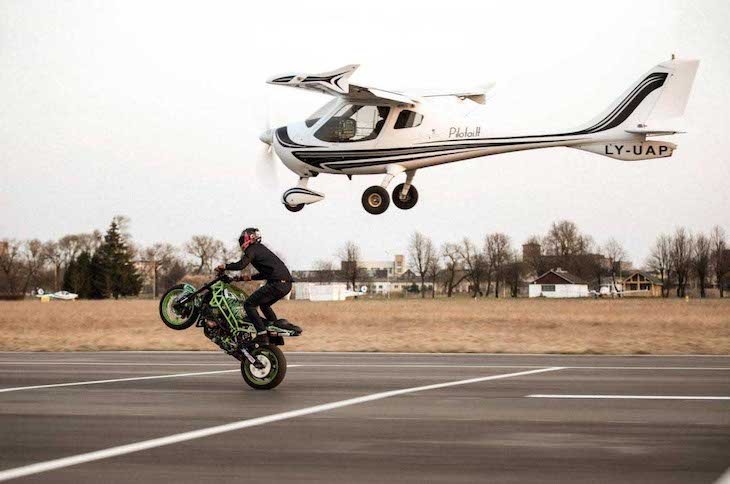 Stuntman Paulius Labanauskas doing wheelie together with the plain