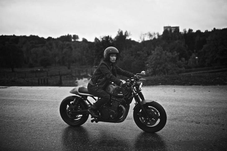 Woman riding cafe racer style bike in a wet weather