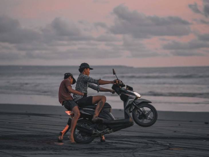 Father and son having fun in Bali beach with their motorcycle