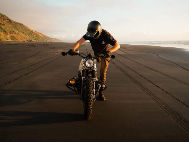 man learning how to ride a motorcycle on a beach